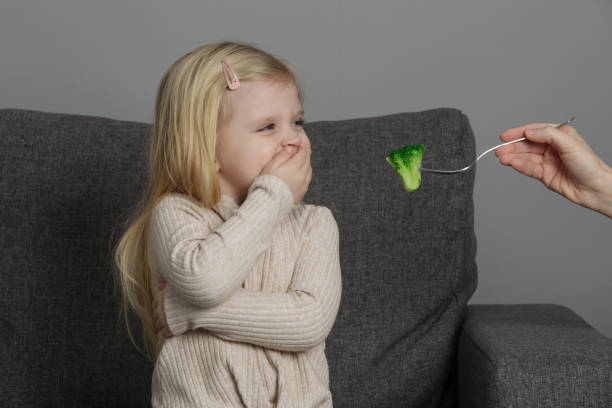 la petite fille ne veut pas manger de brocoli. enfant refusant de manger des légumes. - eating obsessive child toddler photos et images de collection