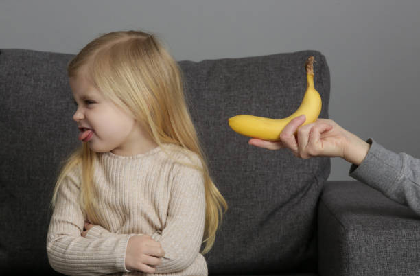어린 소녀는 바나나를 먹고 싶지 않습니다. 과일을 먹는 것을 거부하는 아이. - eating obsessive child toddler 뉴스 사진 이미지