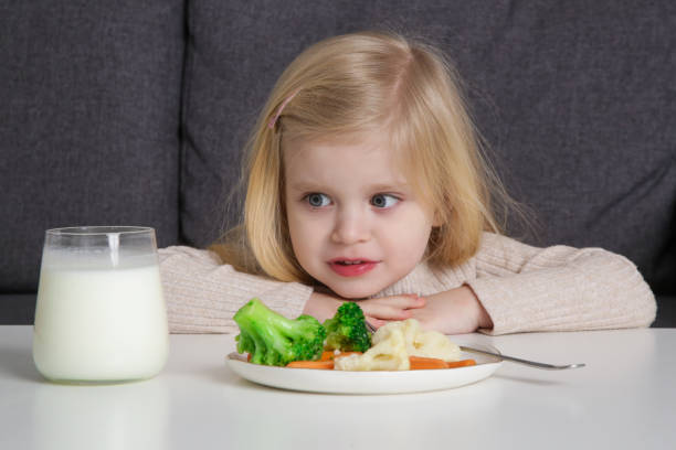 幼児は野菜を食べたくない。彼女の前の皿から野菜を拒否する小さな女の子の肖像画。 - cute disgust carrot caucasian ストックフォト�と画像