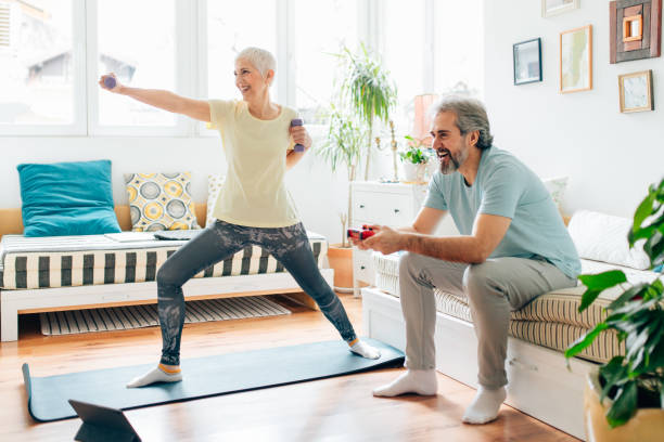 istock Senior woman doing exercises while senior man playing video games on couch 1307223551