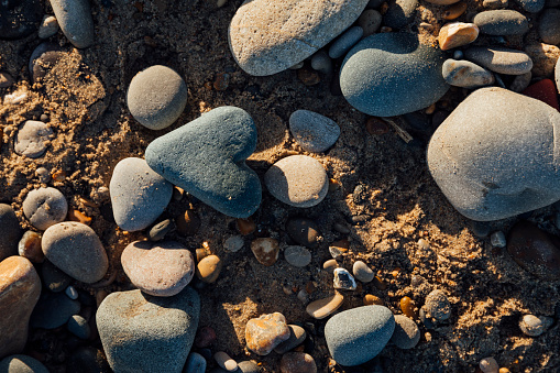 A directly above shot of a heart-shaped stone lying on the surface of a beach in Northeastern England.