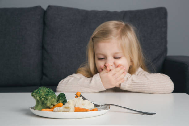 le bambin ne veut pas manger de légumes. verticale de petite fille refusant le légume de l’assiette devant elle. - eating obsessive child toddler photos et images de collection