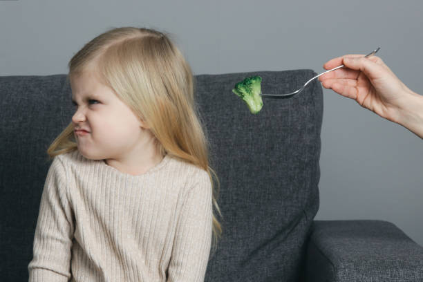 la petite fille ne veut pas manger de brocoli. enfant refusant de manger des légumes. - eating obsessive child toddler photos et images de collection