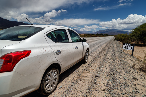 Cachi, Argentina - January 8, 2021: Car stopped next to mileage sign on dirt road near Cachi town at Salta province, on the north of Argentina