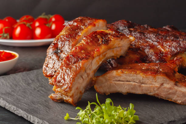 Grilled pork ribs, served on a graphite board with tomatoes