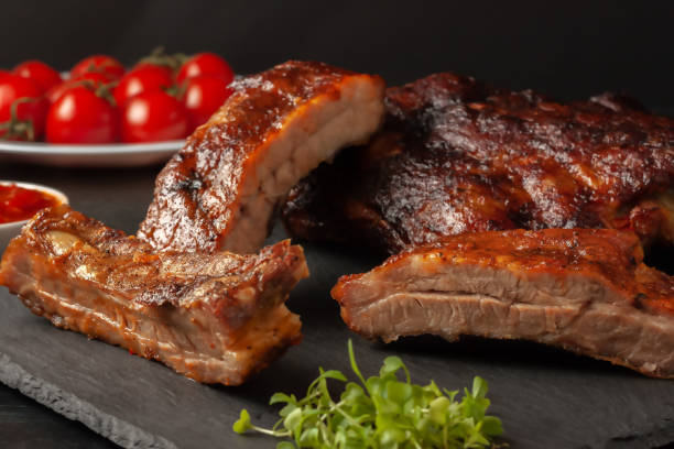 istock Grilled pork ribs, served on a graphite board with tomatoes 1307226402