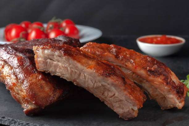 istock Grilled pork ribs, served on a graphite board with tomatoes 1307226403