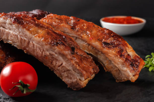 istock Grilled pork ribs, served on a graphite board with tomatoes 1307226410
