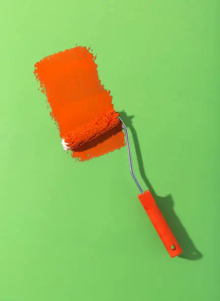 Fresh red paint with paint roller on green background