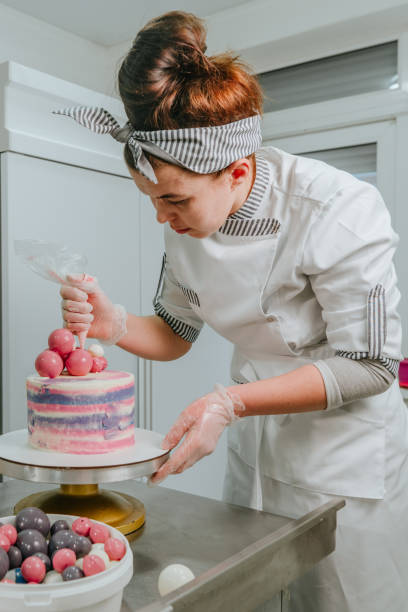 istock Female confectioner decorating birthday cake at confectionery studio 1307229237