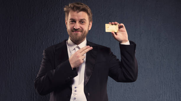 uomo positivo con un tailcoat che punta il dito contro la carta di credito. - platinum card foto e immagini stock