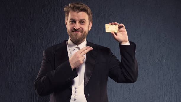 positive man in a tailcoat pointing finger to the credit card. - platinum card imagens e fotografias de stock