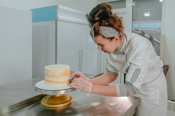 istock Female confectioner decorating birthday cake at confectionery studio 1307229440