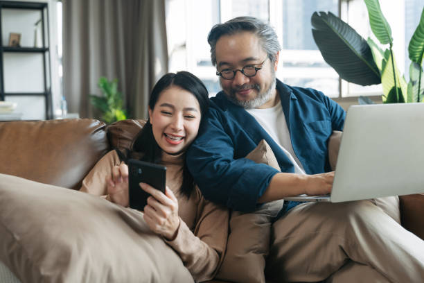 Female showing smartphone to husband in living room at home Female showing smartphone to husband in living room at home 45 49 years photos stock pictures, royalty-free photos & images