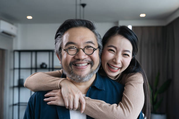 plan rapproché couples asiatiques d’âge moyen souriant pour l’appareil-photo et regardent l’un l’autre. verticale de couples de famille - couple dâge mûr photos et images de collection