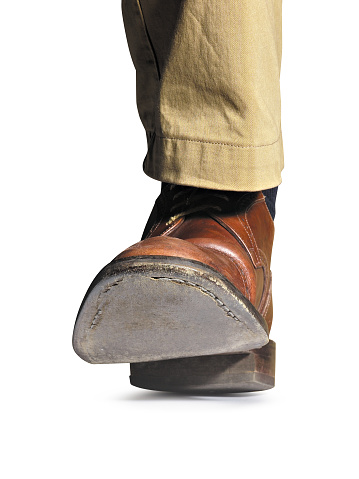 low angle view with detail of the sole of a man's shoe that is walking, isolated on white background