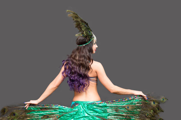istock Dancer holds peacock feathers in her hands, black background view from the back 1307231044