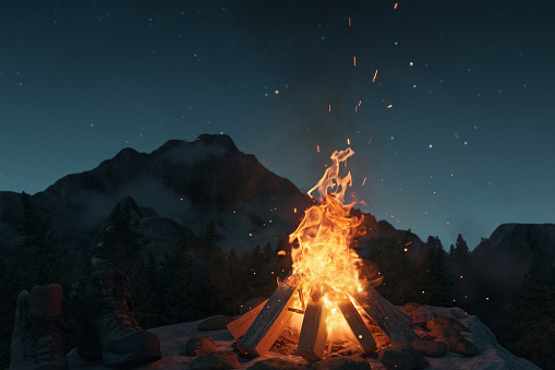 3d rendering of big bonfire with sparks and particles in front of foggy mountain and stary sky