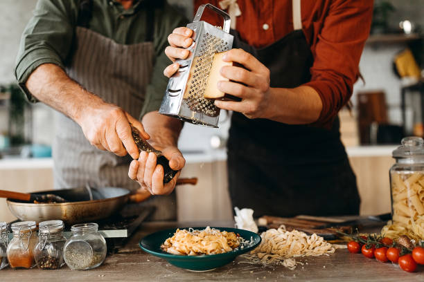 due chef che servono pasta in un piatto - grater foto e immagini stock