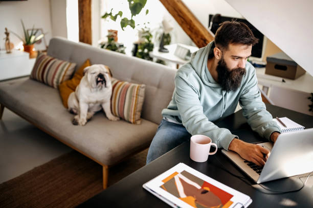 istock Young bearded man working from home with his dog 1307234791