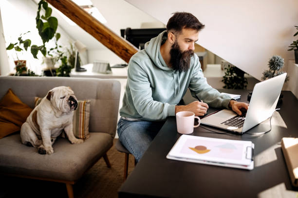 istock Young bearded man working from home with his dog 1307235489