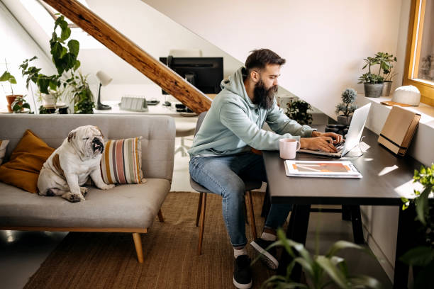 istock Young bearded man working from home with his dog 1307236503