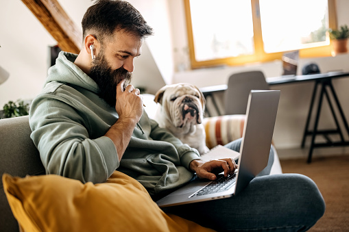 Handsome young man working from home with his bulldog