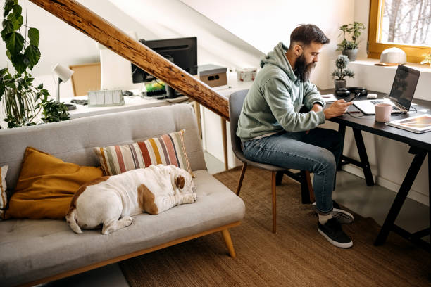 istock Young bearded man working from home with his dog 1307237064