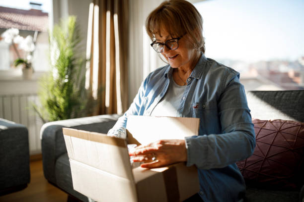 podekscytowana starsza kobieta rozpakowująca zamówienie online - box open merchandise gift zdjęcia i obrazy z banku zdjęć