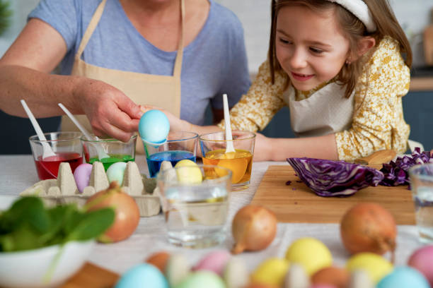 istock Little girl with grandmother dyeing Easter eggs 1307239439