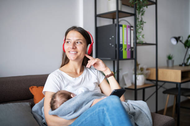 istock Young smiling mother using technology while relaxing and holding her baby. 1307239748