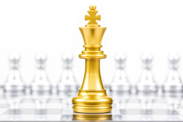 Gold king in battle chess game stand on chessboard against silver chess pawn pieces on opposite side isolated on white background, Leader and teamwork for business achievement strategy concept