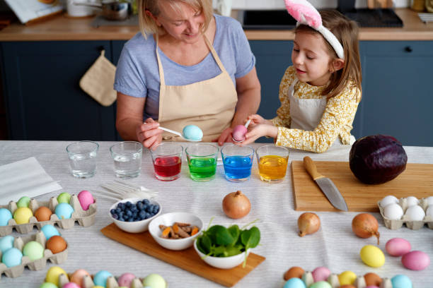 istock Granddaughter with grandmother dyeing Easter eggs on the table 1307240516