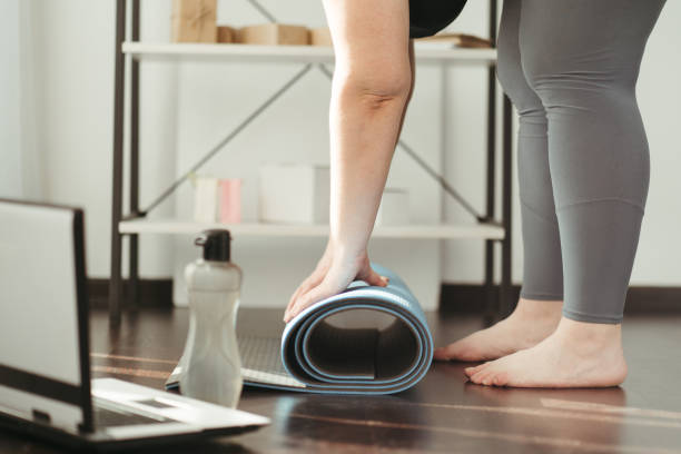 istock Overweight woman rolling yoga mat before workout 1307241347