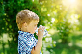 Cute boy drinking a glass of pure water in nature.