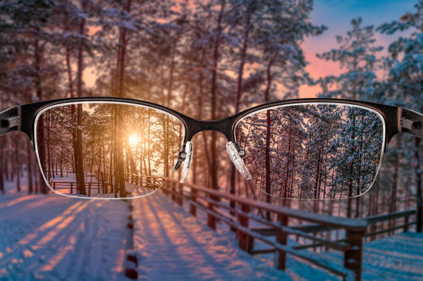 Sunset in forest landscape focused in women's glasses frame. View through eyeglasses. Better vision concept. Colorful view of sunset landscape in glasses.