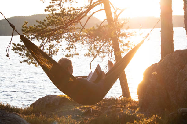 ハンモックに関する読書の女性 - summer women hammock nature ストックフォトと画像