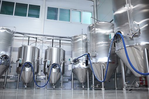 Wide angle background image of distillery and fermentation tanks at modern industrial brewery, copy space