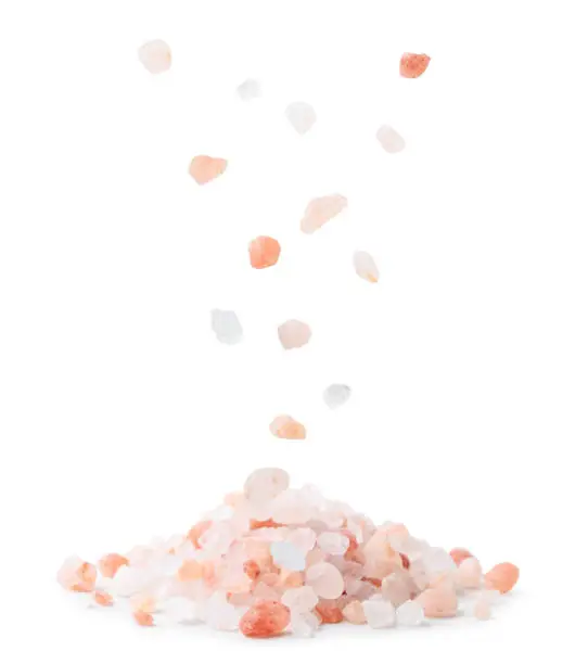 Himalayan pink salt drops on a heap close-up on a white background. Isolated