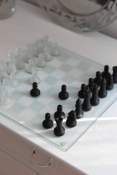 istock Glass chessboard with black and white chess figures on white background. 1307248791
