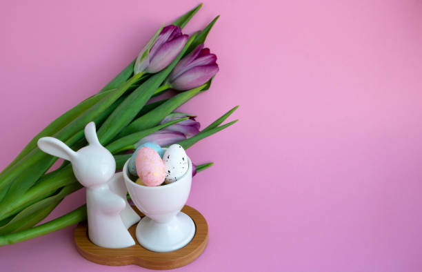 istock White rabbit, Easter eggs and lilac tulips on pink background, Easter celebration concept 1307250444