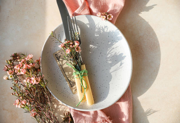 istock Easter table setting background with plate, cutlery set and pink flowers. Empty plate, advertising, menu. Bright sunlight and hard shadows photography trend. 1307251886