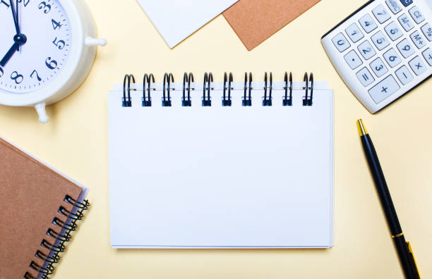 istock On a light background there is a white alarm clock, a calculator, a pen and a notebook with a place to insert text or illustrations. Template 1307252746