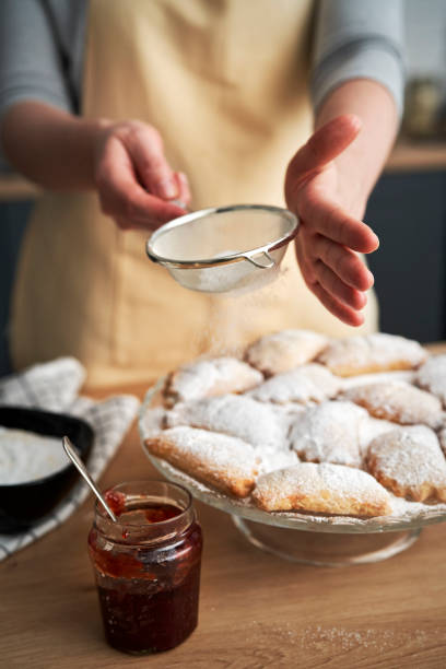 Vertical image of sprinkling and decorating cookies with powdered sugar