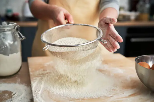 Close up of sifting flour in domestic kitchen