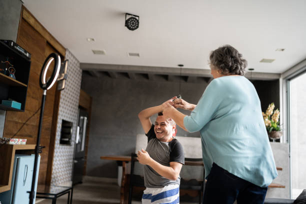Young man with dwarfism and his mother dancing while vlogging at home Young man with dwarfism and his mother dancing while vlogging at home persons with disabilities photos stock pictures, royalty-free photos & images