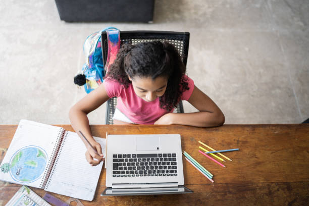 High angle view of girl studying using laptop at home