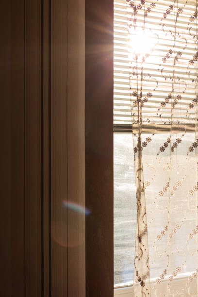 istock Plastic window with blinds and curtains with rays of sun 1307259056