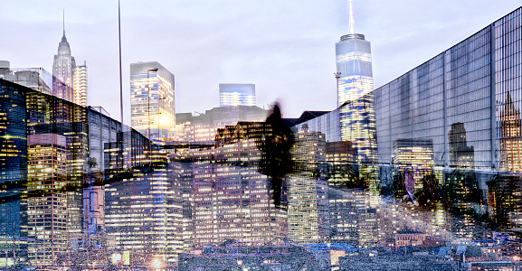 Shot of unrecognizable person walking on a street superimposed over an illuminated cityscape. The city is NYC, Lower Manhattan.