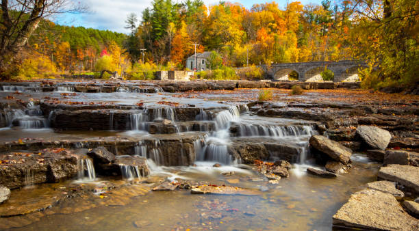 Pakenham Falls in Autumn Long exposure photograph of waterfalls taken on a sunny fall day. The historic Pakenham five stone arched bridge is in the background, surrounded by trees showing fall colours. mississippi river stock pictures, royalty-free photos & images